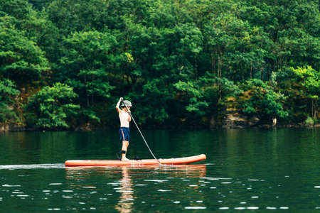 Happy active child on paddle board on waterの写真素材