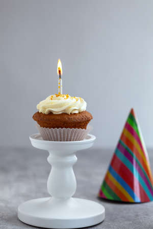 carrot cupcake with cream, burning candle, against the background festive capsの写真素材