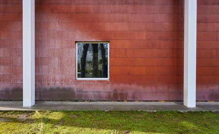 Red wall, white columns and reflection of trees in the window