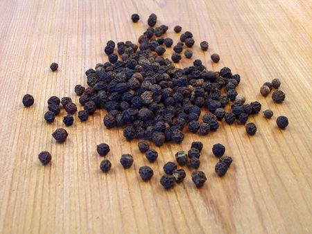 Black peppercorns on a piece of cedar.