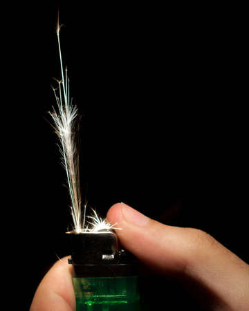 A hand operating a green disposable lighter and sparks being emitted.の写真素材