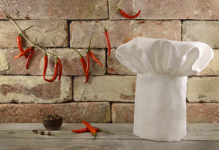 White toque with hot chili peppers on brick wall background の写真素材