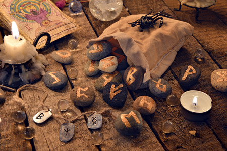 Still life with ancient runes and the tarot cards in candle light. Halloween background, black magic rite or spell, occult and esoteric objects on witch tableの写真素材