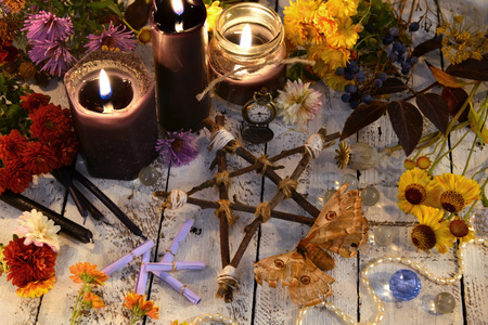 Wooden pentagram with moth - death symbol, black candles and flowers on planks. Occult, esoteric, divination and wicca concept. Halloween vintage backgroundの写真素材