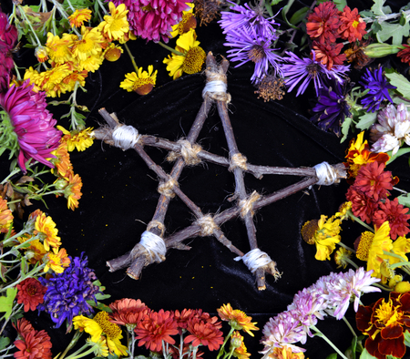 Hand made wooden pentagram in circle of flowers, top view. Occult, esoteric, divination and wicca concept. Halloween vintage backgroundの写真素材