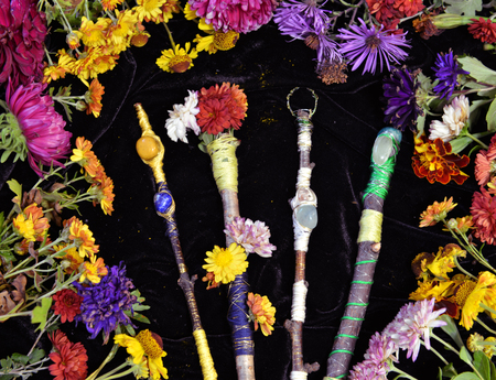 Decorated magic wands in circle of flowers, top view. Occult, esoteric, divination and wicca concept. Halloween vintage backgroundの写真素材