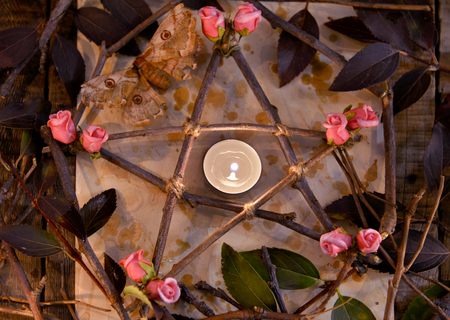 Wooden decorated pentagram with leaves, flowers and candle on paper, top view. Occult, esoteric, divination and wicca concept. Halloween vintage backgroundの写真素材