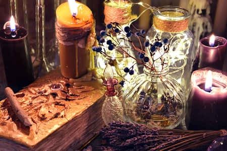Evil book with black candles, glass bottles, and herbs on witch table. Occult, esoteric, divination and wicca concept. Halloween background with vintage objectsの写真素材
