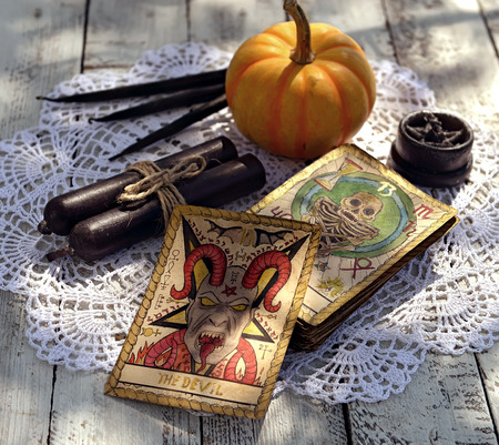 Tarot cards with pumpkin and black table on fortune teller table. Mystic background with ritual objects, occult, fortune telling and halloween conceptの写真素材