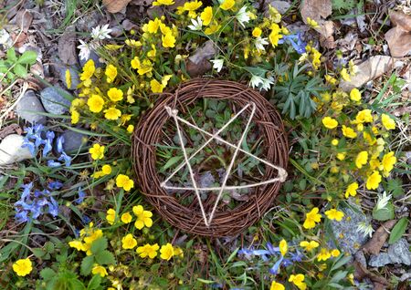 Top view of wooden pentagram in grass and flowers. Wicca, esoteric, divination and occult concept with magic objects for mystic rituals, Halloween, Beltane backgroundの写真素材