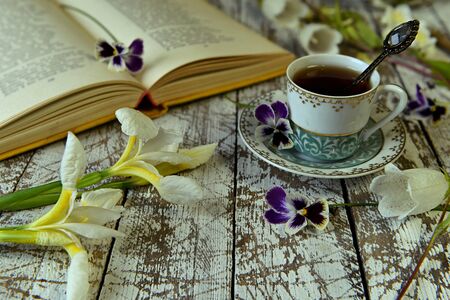 Open book of poetry, old cup of tea and flowers on table.  Vintage still life, poetry and literature reading conceptの写真素材