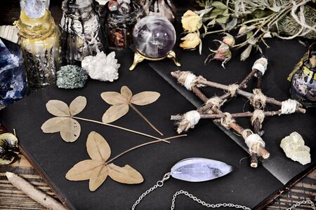 Creepy still life with open book, pentagram, four-lead clover and crystals on witch table. Esoteric, wicca and occult background, fortune telling and divination ritual, mystic conceptの写真素材
