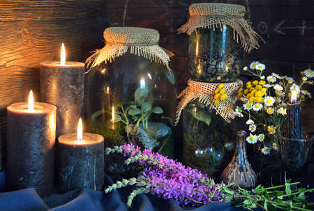 Black candles and magic bottles with plants and herbs on witch table.  Esoteric, gothic and occult background, Halloween mystic concept.の写真素材