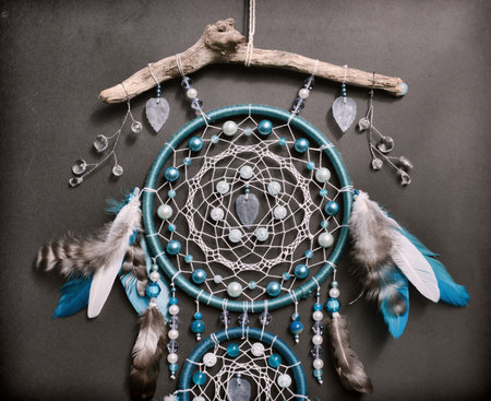 Close up of beautiful boho styled dreamcatcher with blue feathers and beads against black.  Mystic background with dream catcher, esoteric and occult conceptの写真素材
