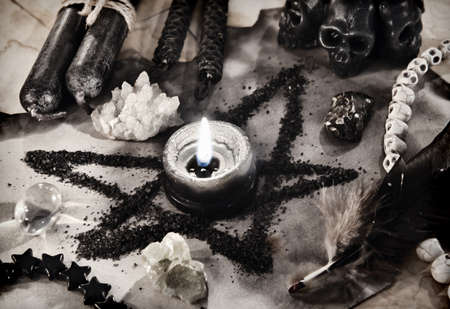 Pentagram symbol made of black salt with burning candle on old paper with magic crystals. Esoteric, gothic and occult background, Halloween mystic concept.の写真素材