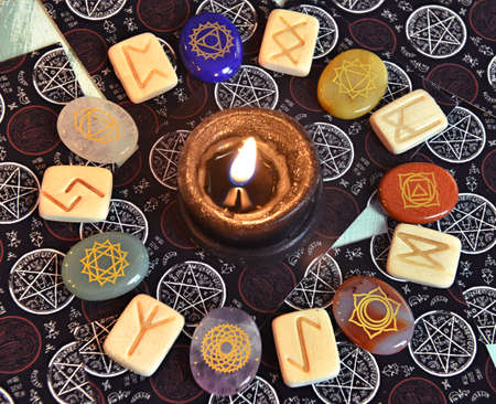Still life with runes and chakra crystal stones with burning candle and tarot cards.  Esoteric, gothic and occult background, Halloween mystic concept.の写真素材