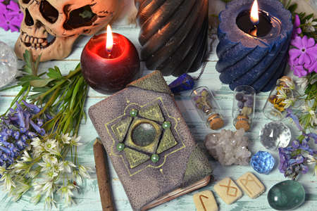 Still life with decorated diary book, runes, crystals and burning candles on witch table. Esoteric,...