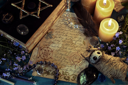 Voodoo doll with magic book of spells and candles on witch ritual table. Occult, esoteric and fortune telling still life. Mystic background with vintage objectsの写真素材