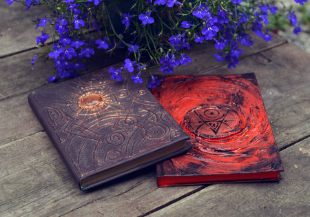 Magic books of spells and flowers on wooden old table. Occult, esoteric, wicca and divination...