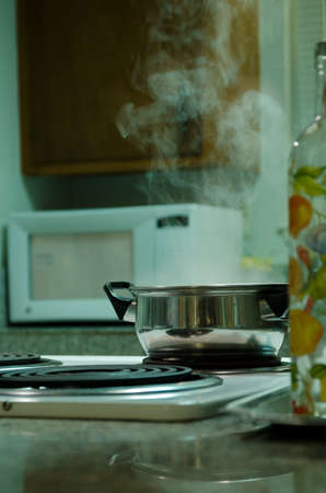 pot with boiling water standing in the stove, fluorecent lightの写真素材