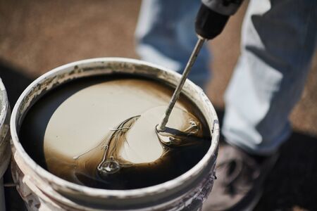Person mixing white paint in bucket. Home renovation, walls color change, diy conceptの写真素材