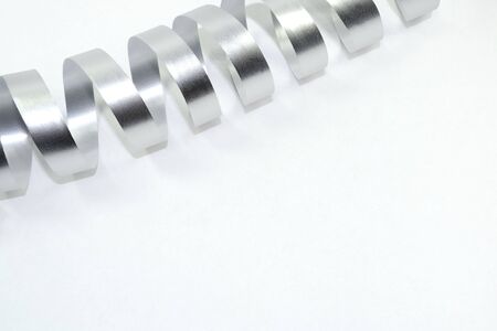 Bright silver curled ribbon. White backgroundの写真素材