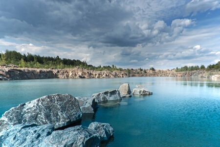 Dark dramatic landscape stormy sky over lake with rocksの写真素材