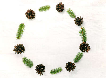 Christmas wreath made of pine cones and sprigs firon the white wooden background. Natural decor ornament for holiday card. Xmas card. Happy New Year. Top viewの写真素材