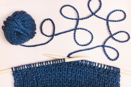 Knitting by wooden knitting needles. Woolen yarn on background. Process of knittingの写真素材