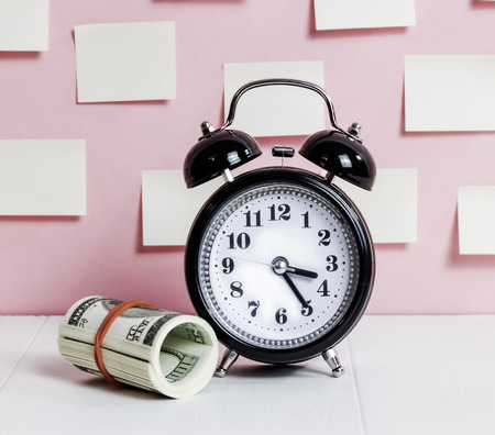 Dollars rooled and alarm clock - Concept saving  moneyの写真素材