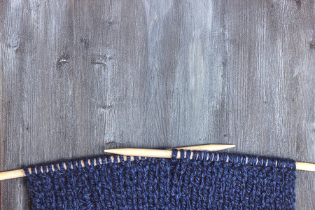 Knitted scarf of woolen blue thread - wooden knitting needles in a yarnes