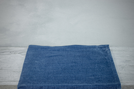 Empty tablecloth or napkin on wooden table over grunge grey background