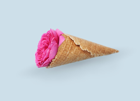 Pink flowers with icecream cone on blue background. Flat lay. Summer minimal conceptの写真素材