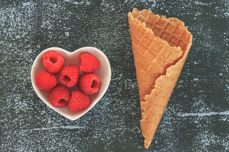 Fresh raspberries in a waffle cup horn on black background. concept of the sweet fruit menu....