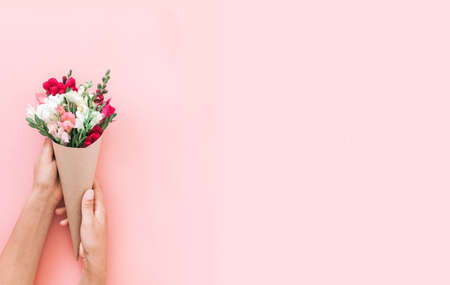Roses, Snapdragon bouquet in cone on pink background, flat lay, top view. Snapdragon