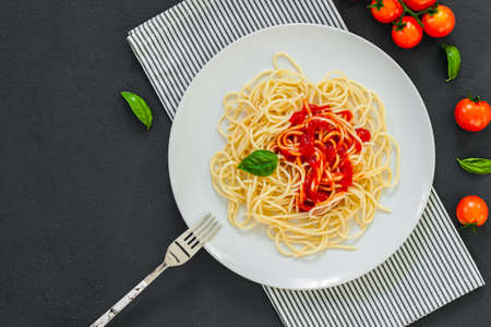 ? lassic italian spaghetti pasta with tomato sauce and basil on plate on dark table. View from above, horizontalの写真素材