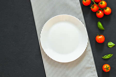 Empty plate. ? lassic italian food background tomato, basil on dark table. Top view.