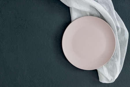 Empty pink plate on black table and napkin. Food background for menu, recipe. Table setting. Flatlay, top view. Mockup for restaurant dishの写真素材