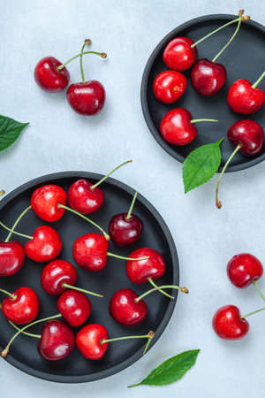 Cherry with leaf on plate and water dropsand on gray stone table. Ripe ripe cherries. Sweet red...
