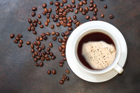 Coffee cup and coffee beans on dark table. Top view with copyspace for your text.