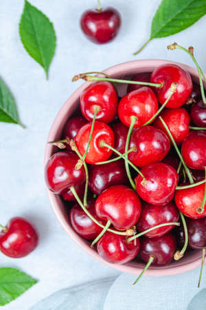 Cherry with leaf on plate and water drops on gray stone table. Ripe ripe cherries. Sweet red...