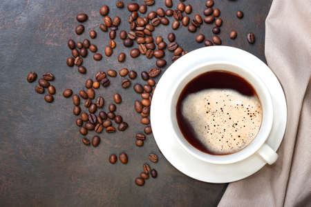 Coffee cup and coffee beans on dark table. Top view with copyspace for your text.
