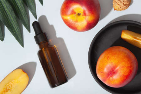 Bottle of peach oil, essential on light blue background. The concept of aroma oil, ingredients of aroma oil, or aromatherapy.の写真素材