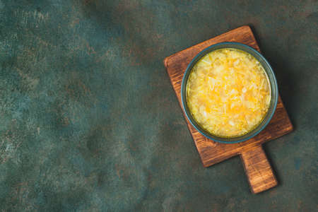 Chicken soup vegetables on black bowl on dark black stone table. Black cooking background