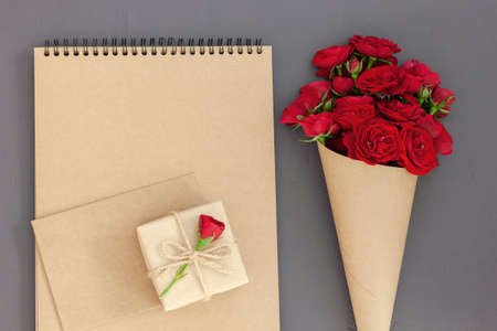 Red rose bouquet wrapped vintage craft paper. Greeting card for holiday text. Top view, flat lay