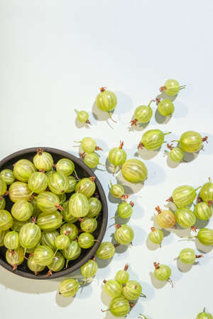Ripe green gooseberry berry in plate bowl. Green gooseberry on light blue background. Top viewの写真素材