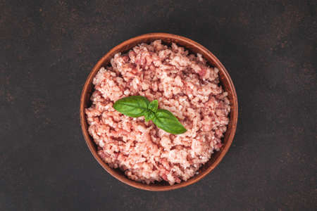 Raw minced meat in bowl on dark table and ingredients. Ground meat with ingredients for cooking on...