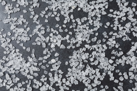 Sea salt on black stone table. Top view, flat lay. Food background with copy space.
