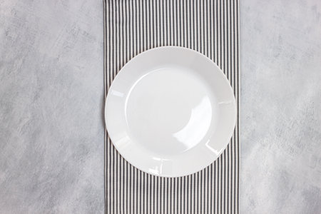 Empty plate on tablecloth on marble table. gray background. Mockup for menu and product of food in...