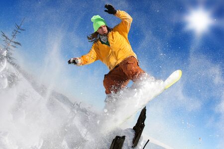 Snowboarder jumping against blue sky の写真素材